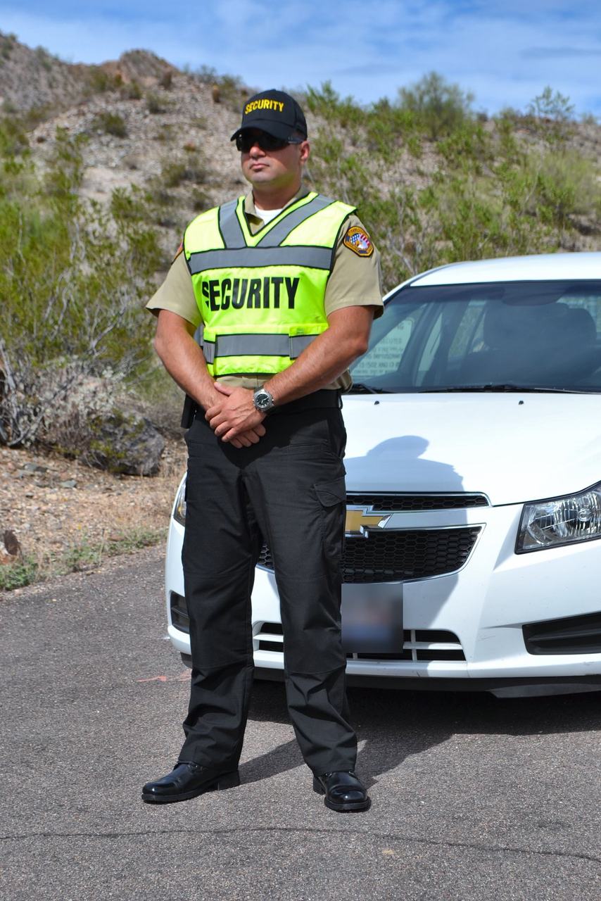 SecureOne security officer standing beside a patrol car